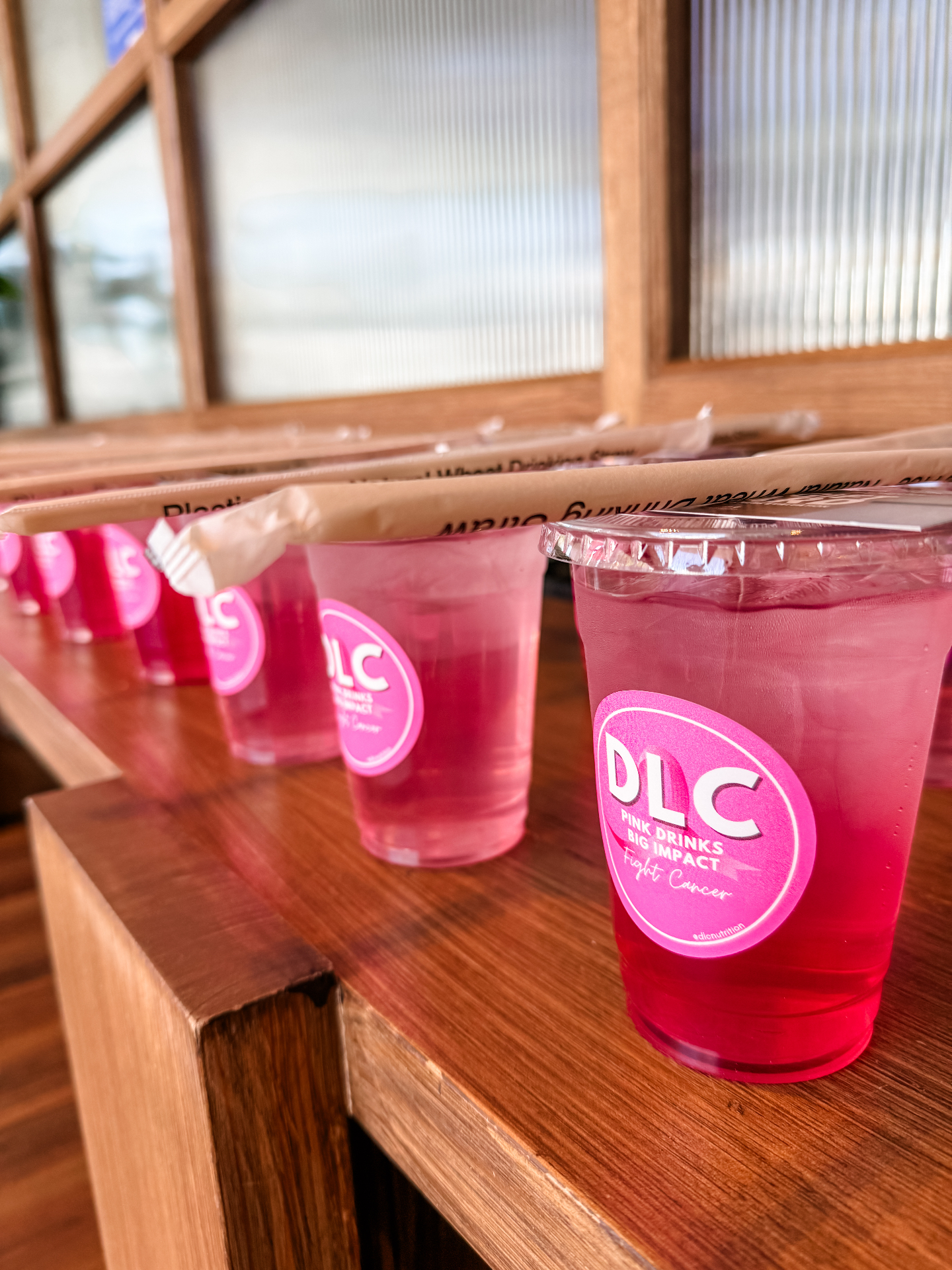 Row of DLC pink drinks lined up on a wooden counter